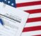 I-589 Application for asylum and for withholding of removal blank form lies on United States flag with blue pen from Department of Homeland Security close up