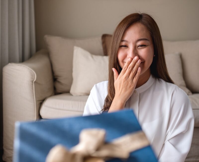 Portrait image of a surprised young woman receiving a gift box